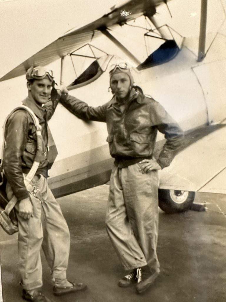 Bob Russell beside an open cockpit training plane with instructor.